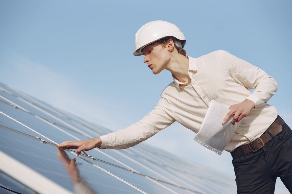 Field engineer in a hard hat inspecting rooftop electrical work
