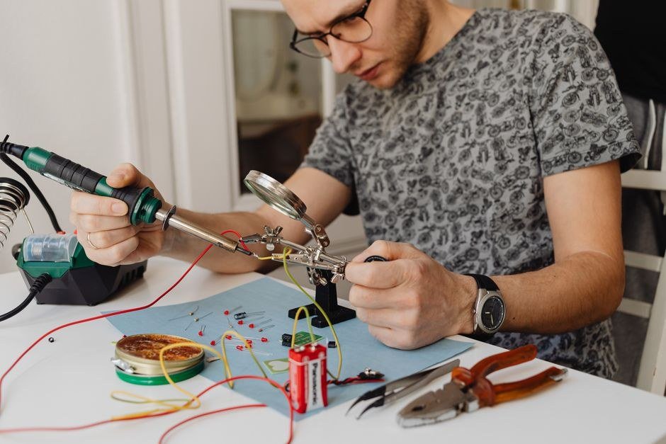 Electrician testing circuits with a digital multimeter at a workbench